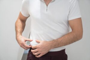 Man in white shirt pinching belly fat