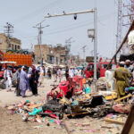 People and police officers in plain clothes gather after a blast at a market in Lakki Marwat