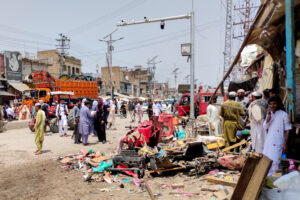 People and police officers in plain clothes gather after a blast at a market in Lakki Marwat
