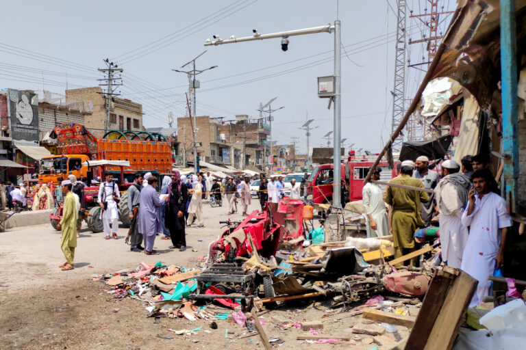 People and police officers in plain clothes gather after a blast at a market in Lakki Marwat