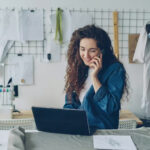 Small business owner on the phone and laptop in her shop, reviewing UAE corporate tax for small businesses