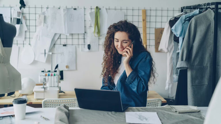 Small business owner on the phone and laptop in her shop, reviewing UAE corporate tax for small businesses
